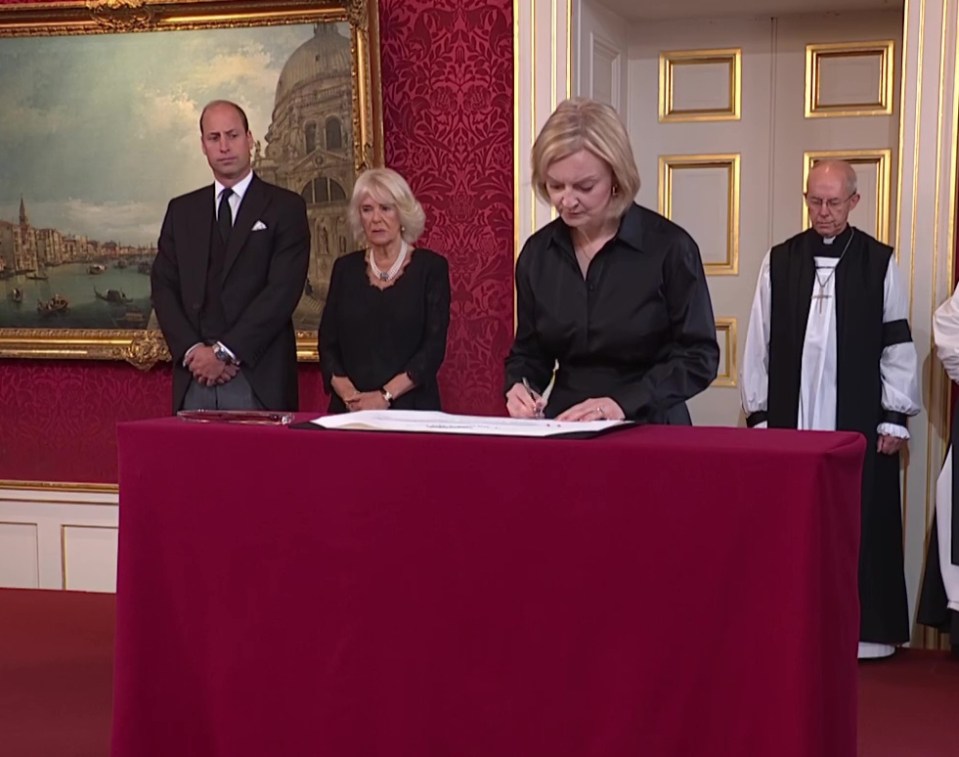 PM Liz Truss signs the proclamation as Prince William and Camilla, the Queen Consort, look on