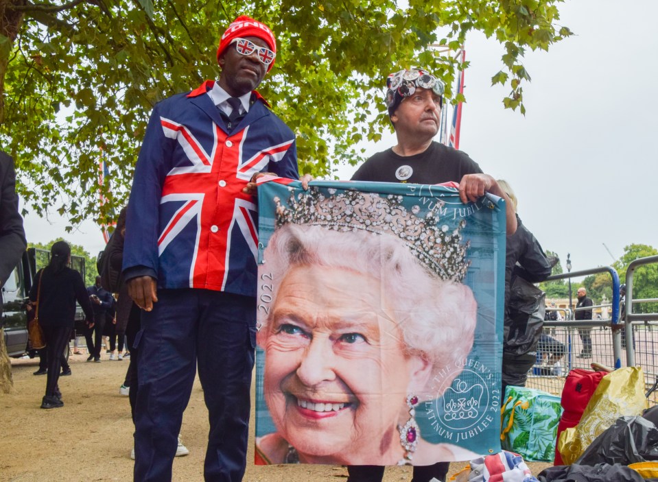 Royal superfan John Loughrey (right) and another fan hold a banner with a picture of Queen Elizabeth II