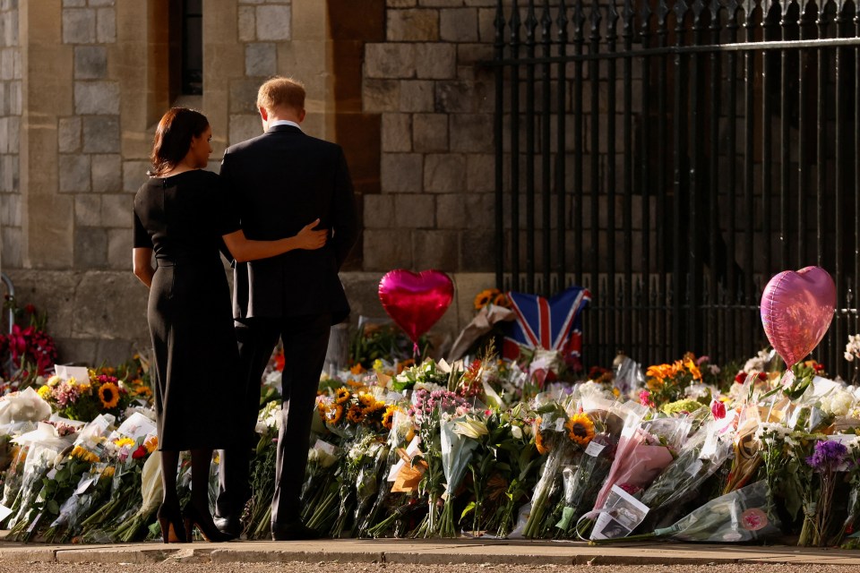 Meghan comforts Harry next to flowers laid in memory of the Queen