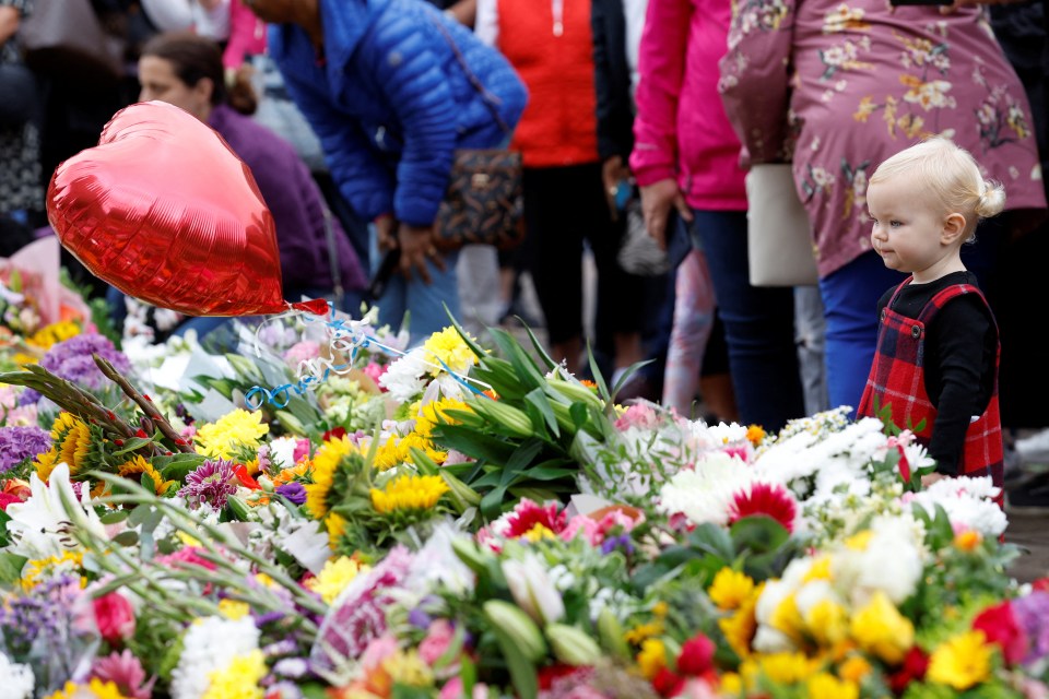 A little girl looks on as people leave flowers outside Windsor Castle