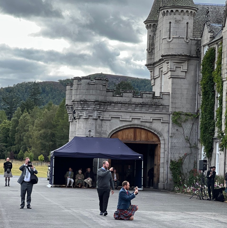 The Queen sheltered under a gazebo at her Scottish home as she watched the band play