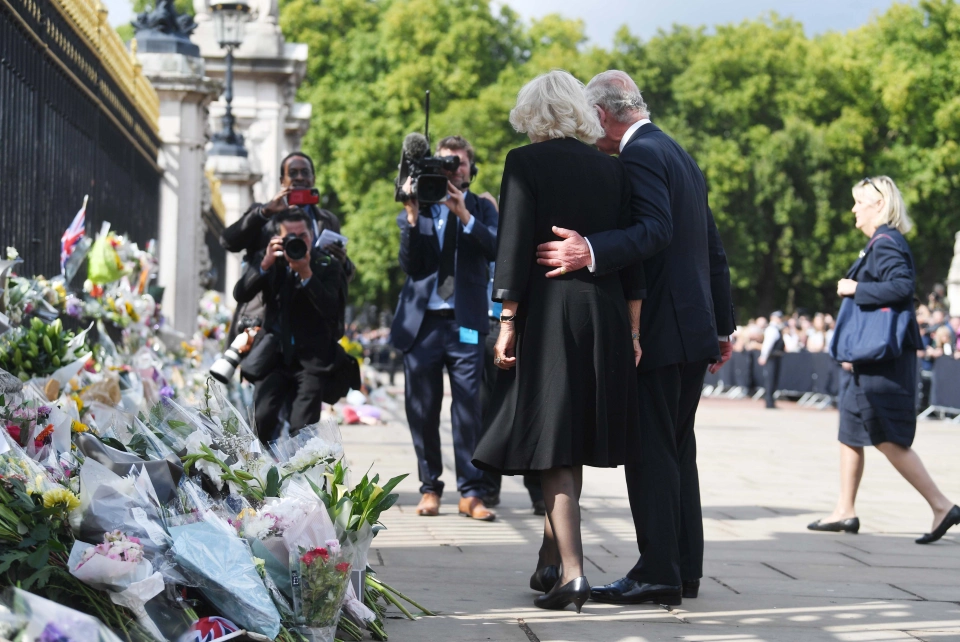 Charles pauses to look at floral tributes to his mother while with Queen Camilla