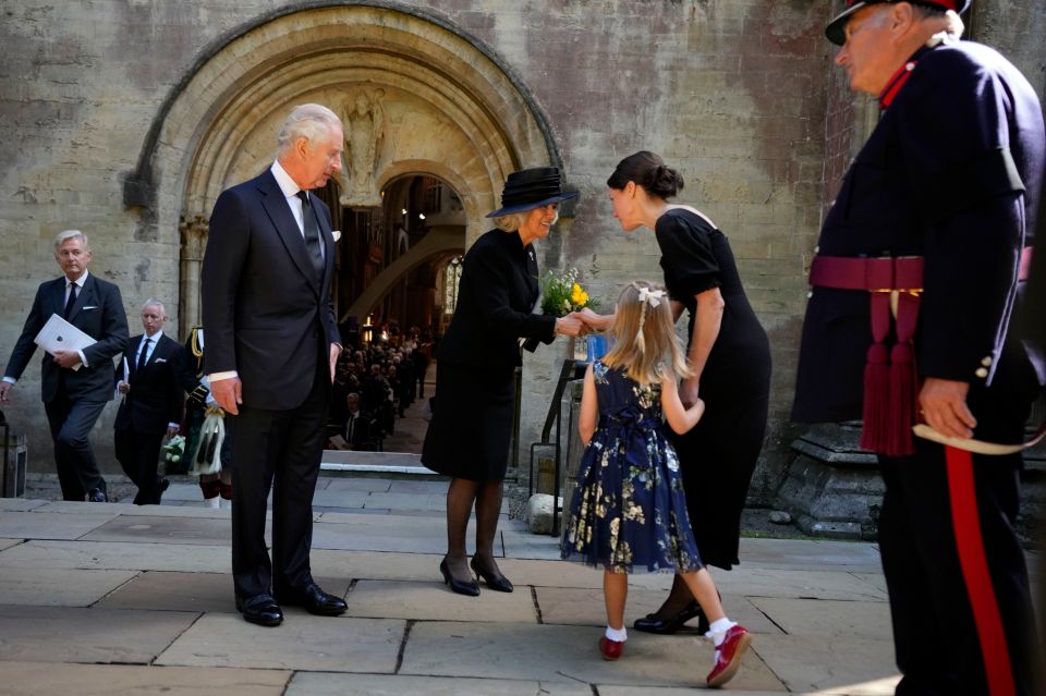 The Queen Consort gets a bunch of flowers from a little girl