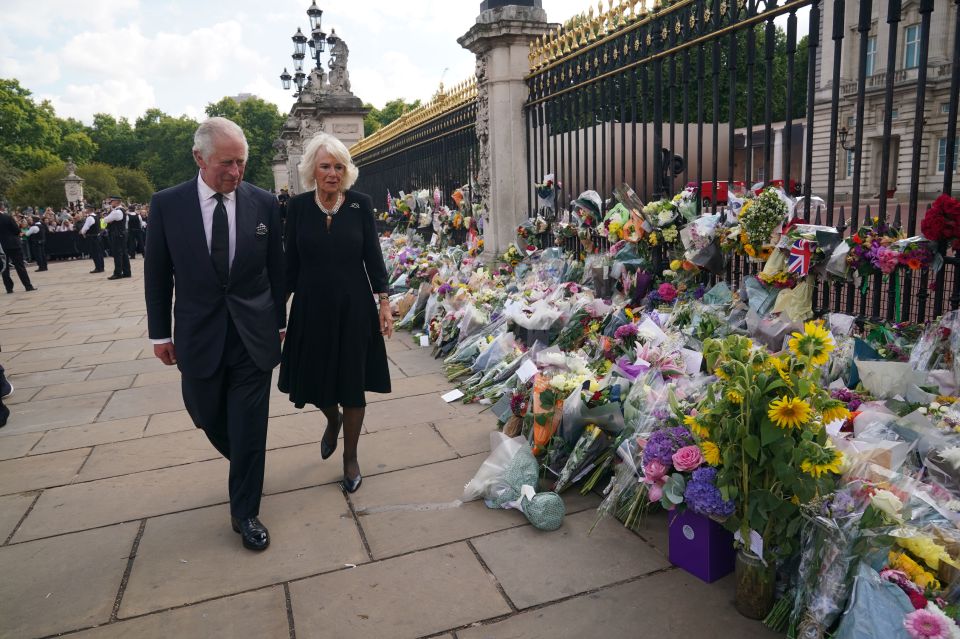 Charles and Camilla appeared emotional as they walked past hundreds of floral tributes left for Queen Elizabeth at the Palace gates