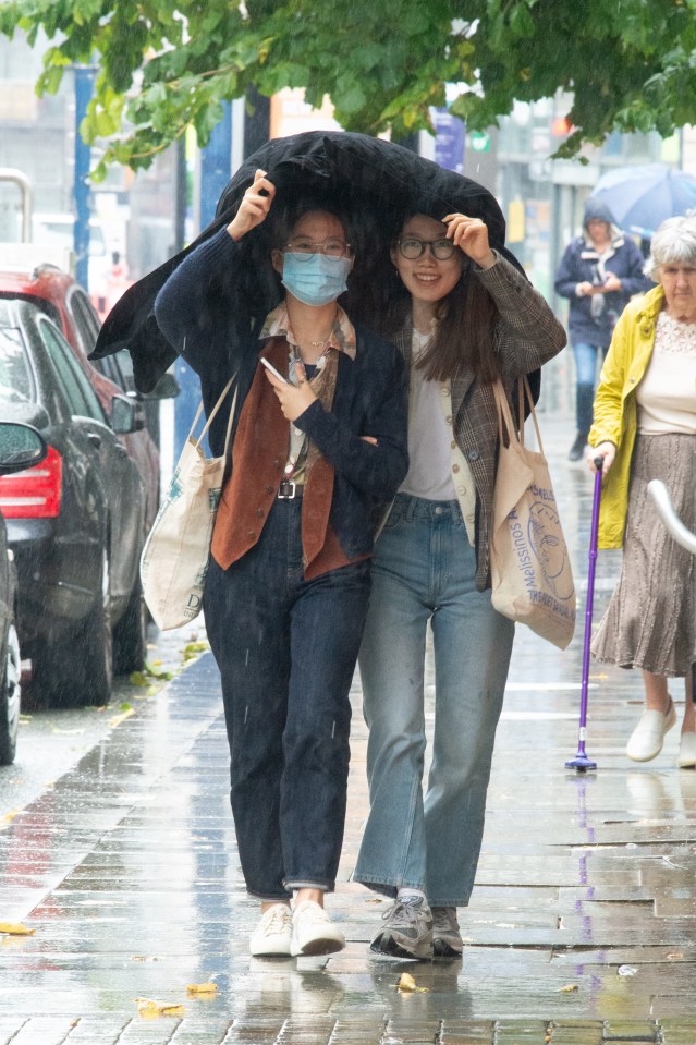 Pals try to keep themselves dry while their out and about in Manchester