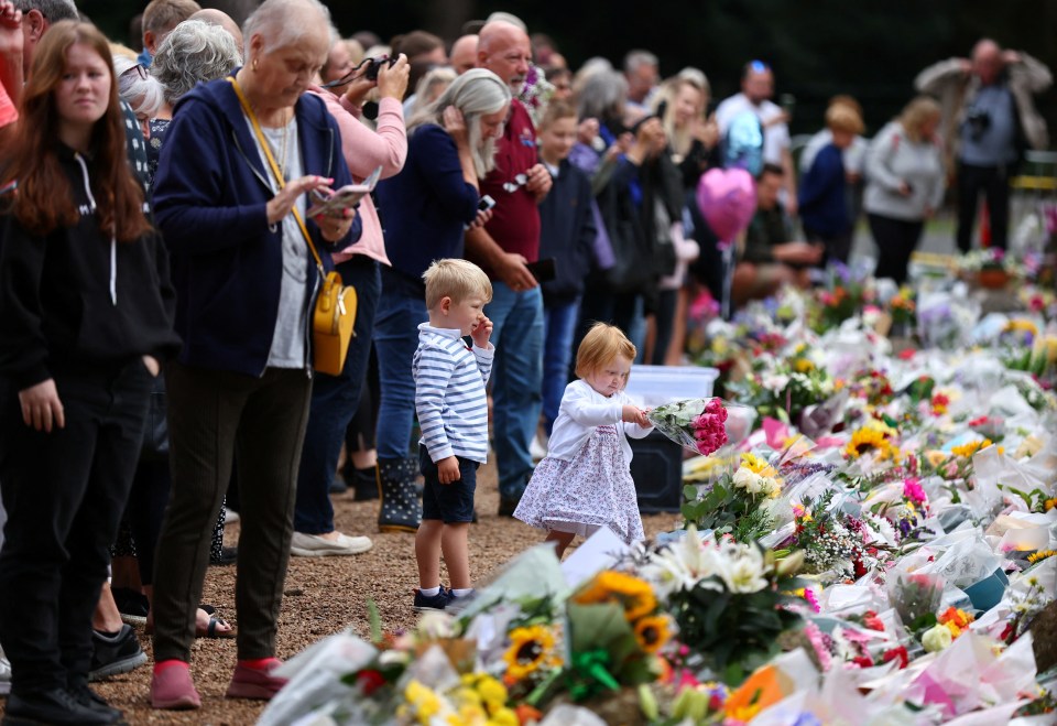 A little girl prepares to lay a bouquet at the gate of the Queen's Sandringham estate in Norfolk