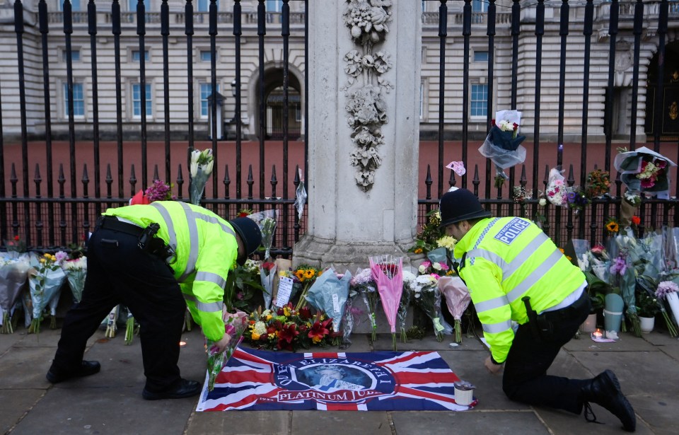 Police officers lay flowers outside Buckingham Palace today