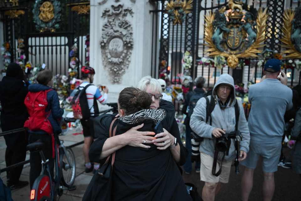 Mourners embrace outside the Queen's London residence today