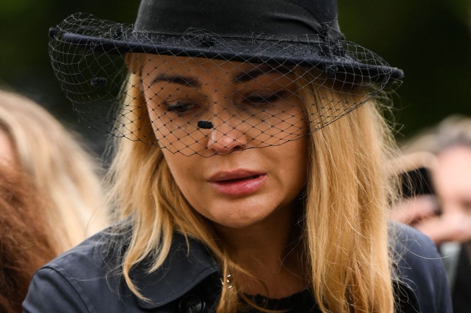 A woman wearing a black veil weeps outside the Palace