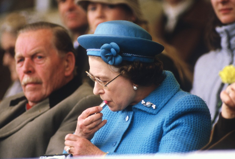 The Queen pictured applying lipstick in the Royal Box at the Windsor Horse Show