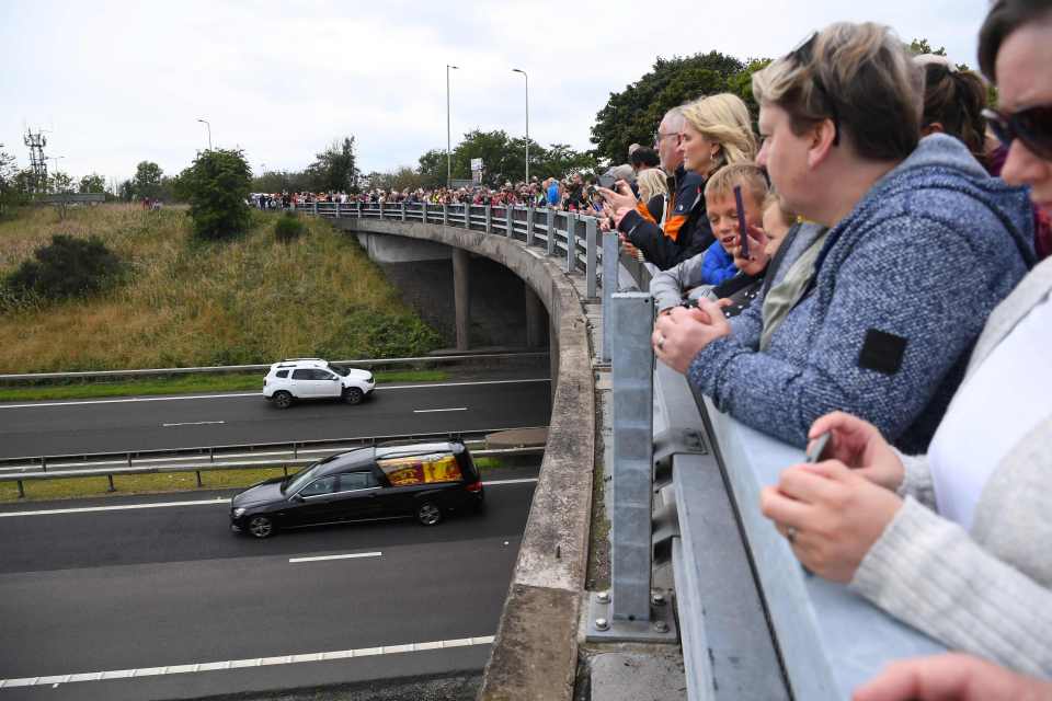 Crowds on a bridge watch the hearse head along the M90 at Kinross