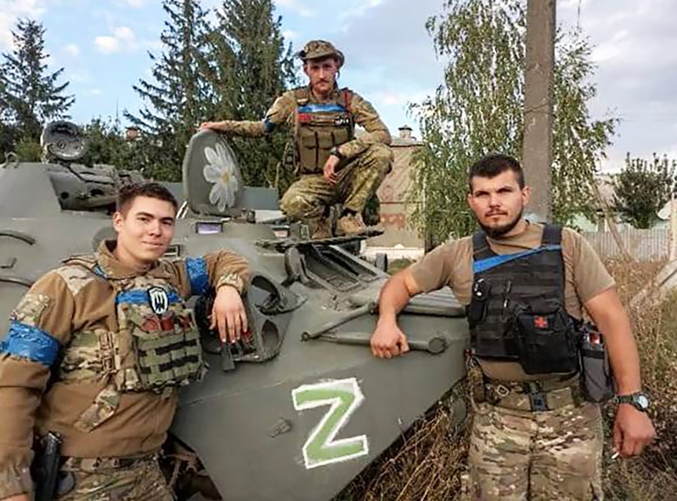 Victorious Ukrainians next to a captured Russian vehicle