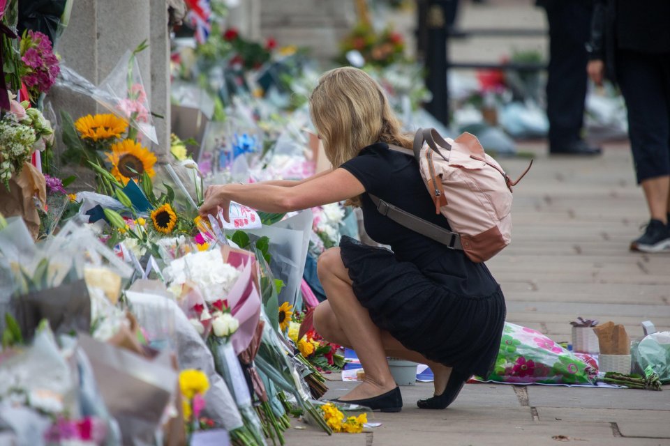 A woman leaves flowers at the Palace gates