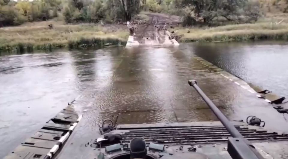 A Ukrainian tank traverses a submerged bridge over the River Oskil