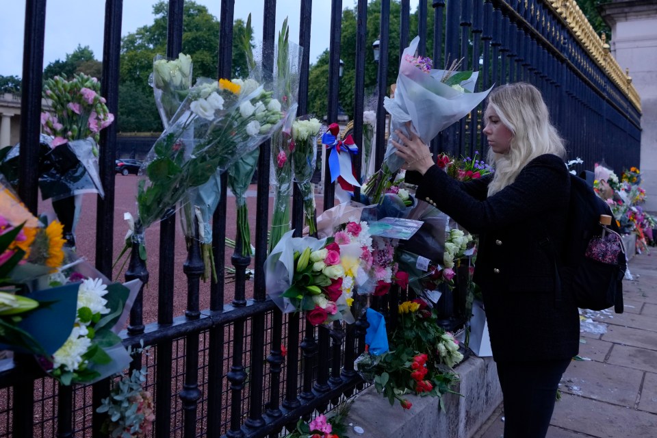 A woman leaves flowers at the Palace