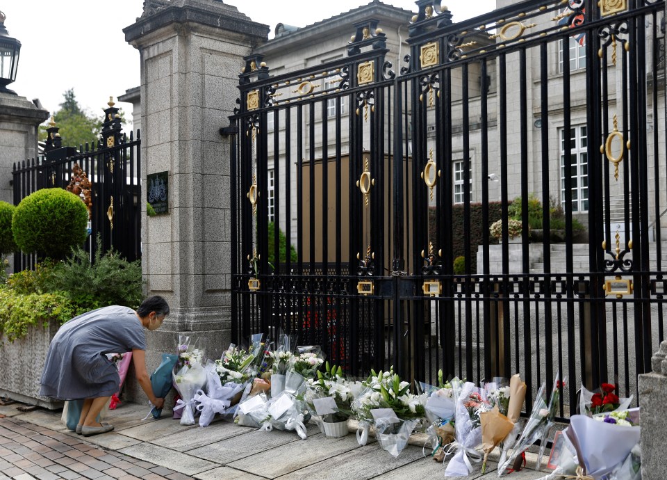 A woman leaves flowers to mourn the death of Queen Elizabeth outside the British Embassy in Tokyo, Japan