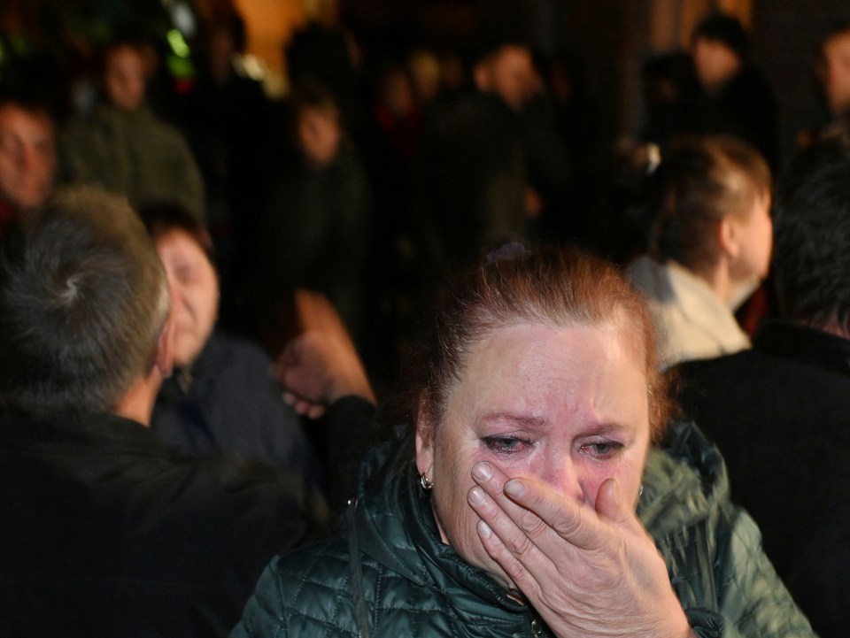 A woman weeps as people bid farewell to reservists drafted to Ukraine