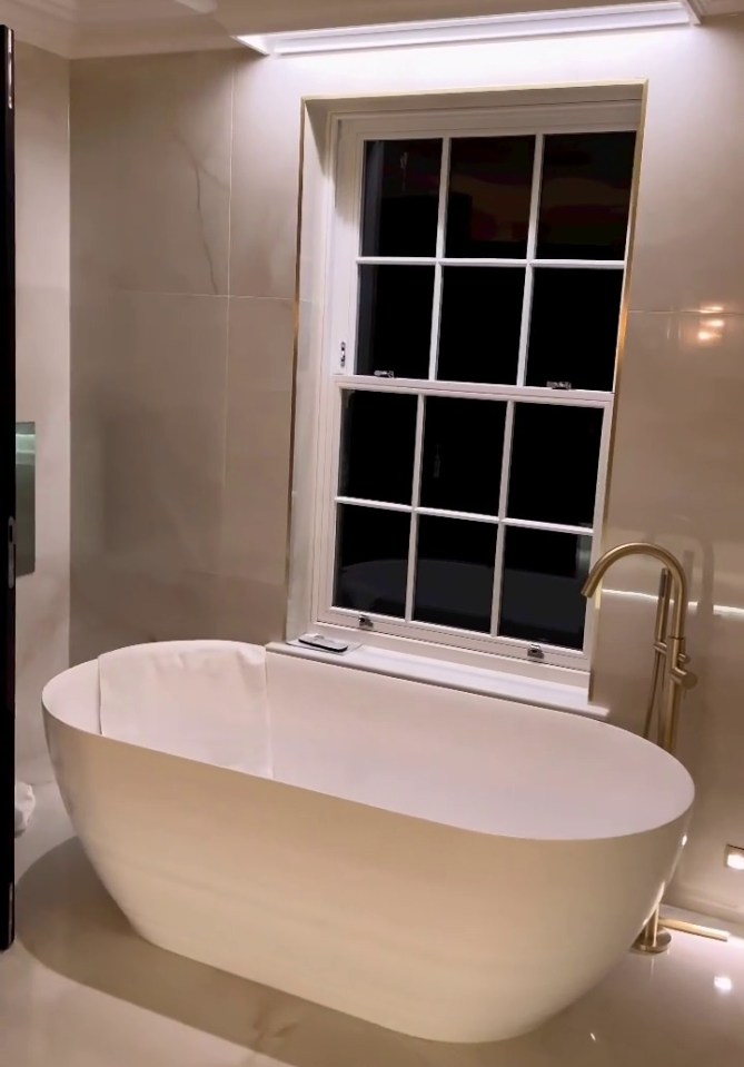 A deep bathtub is seen perched by one of the windows in a video