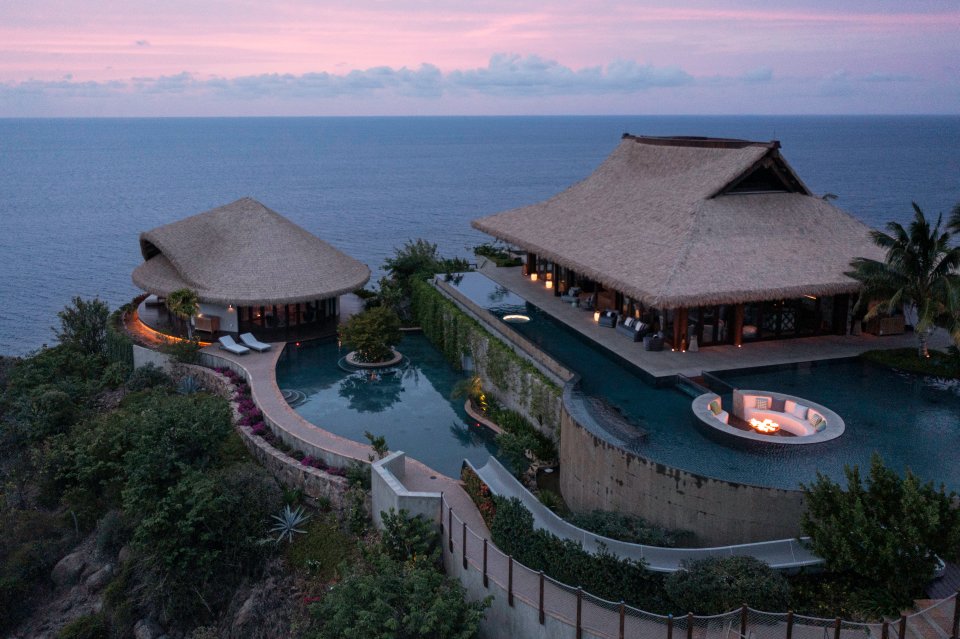 A hidden DJ booth rises from the outdoor deck overlooking the two-story infinity pool