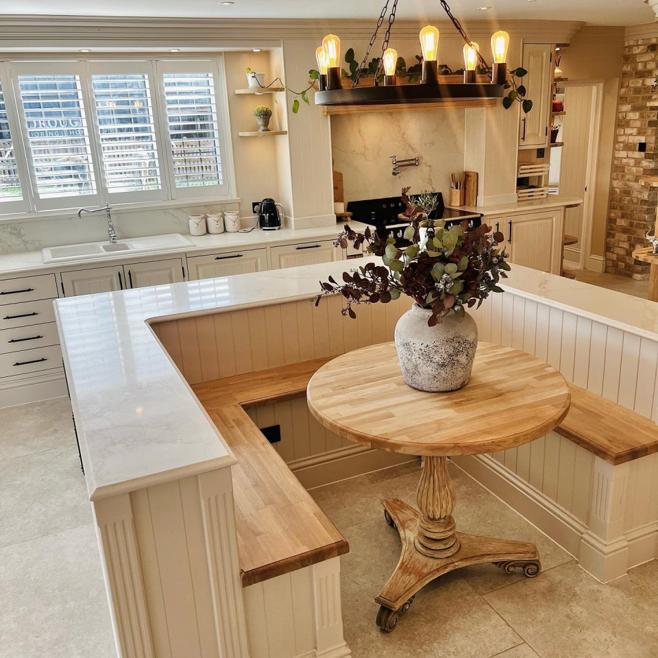 The kitchen features benches and a table inside the kitchen island