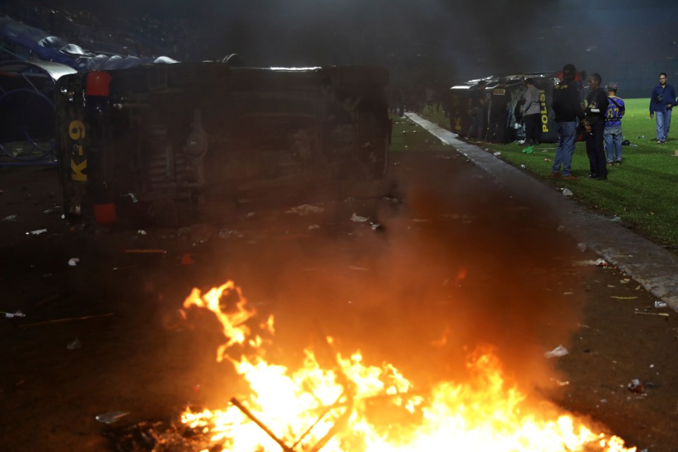 Plain-clothed officers stand near the wreckage of police vehicles damaged during a clash