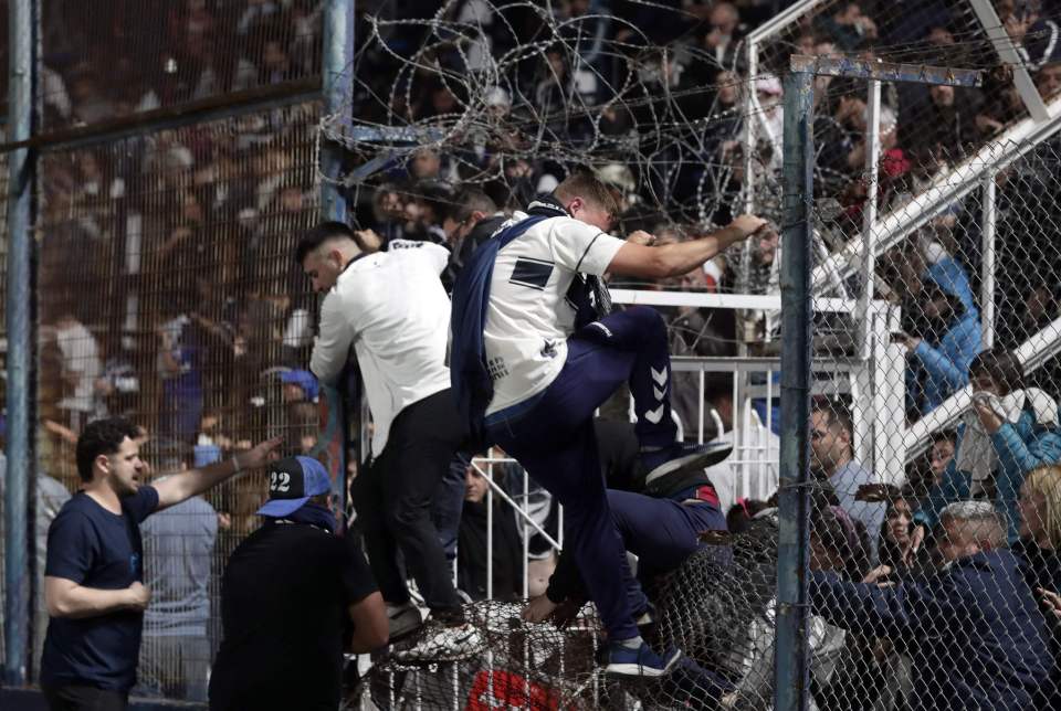 Fans climb from the stands onto the pitch