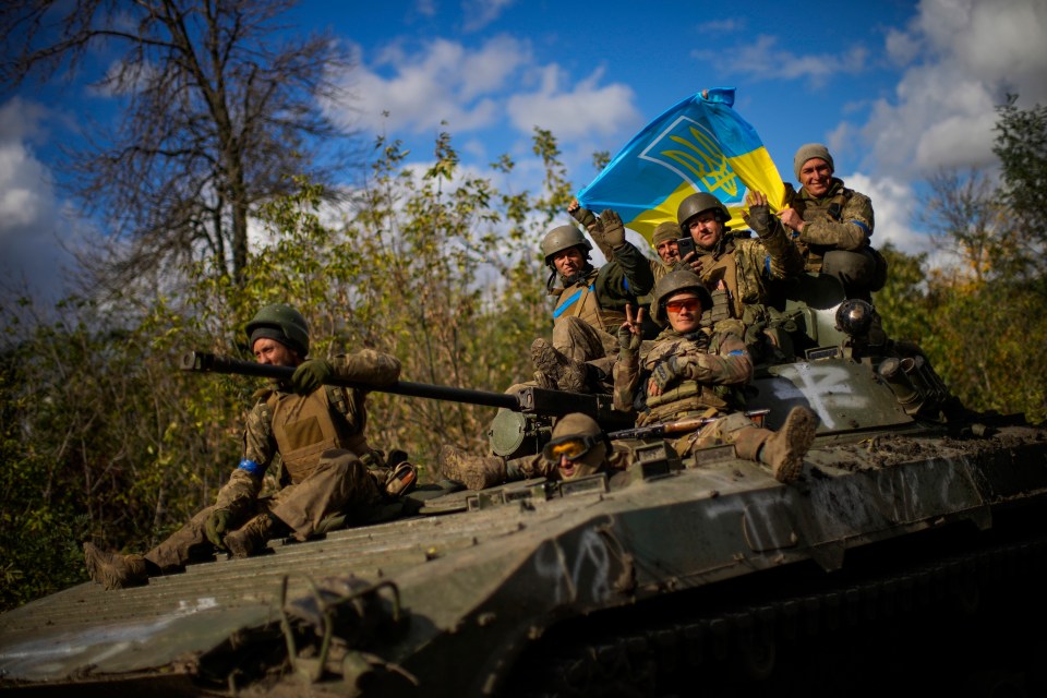 Victorious Ukrainian soldiers with their flag on an armoured vehicle