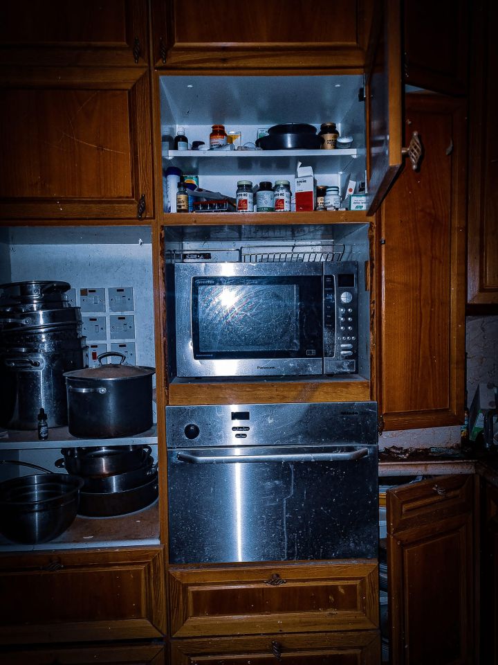 The kitchen still has utensils and a microwave in it