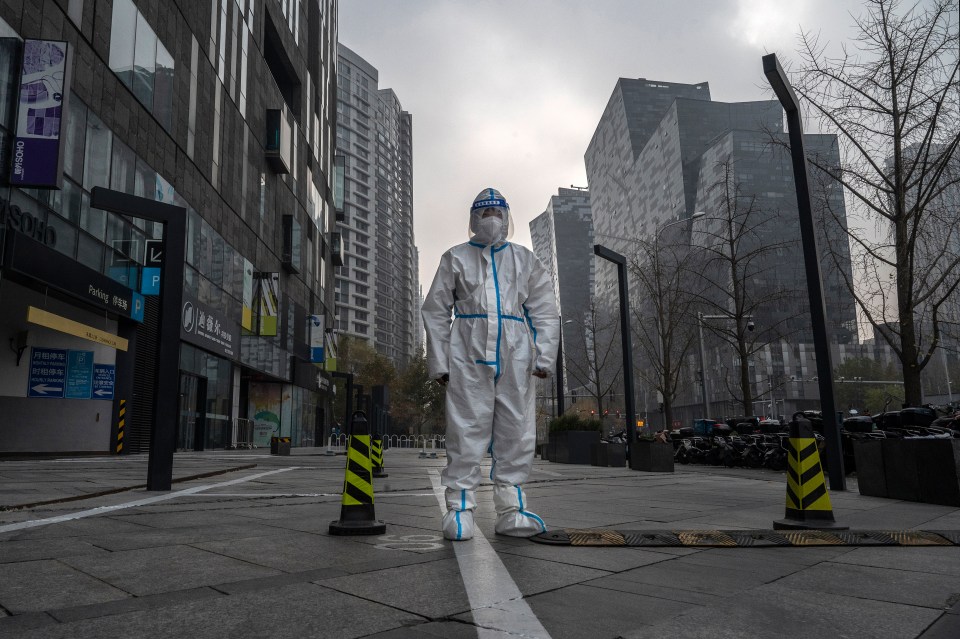 A hazmat suited lockdown  enforcer on the deserted streets of Beijing