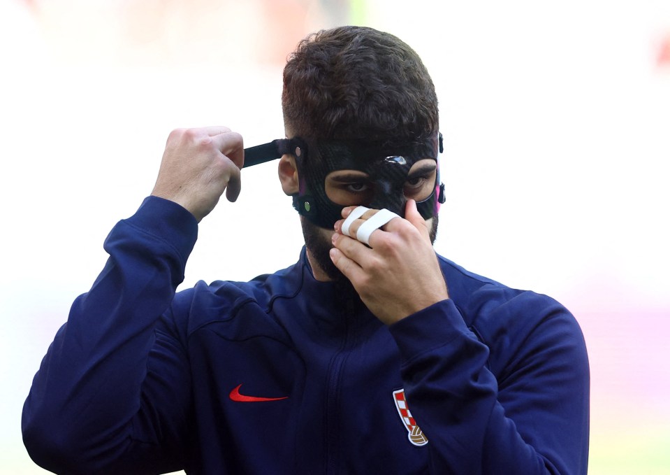 Josko Gvardiol puts on his face mask after the anthems at the World Cup in Qatar