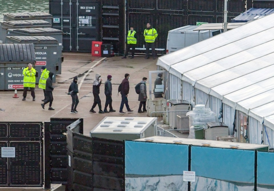 People are escorted ashore after they were picked up in the English Channel at Dover Dock