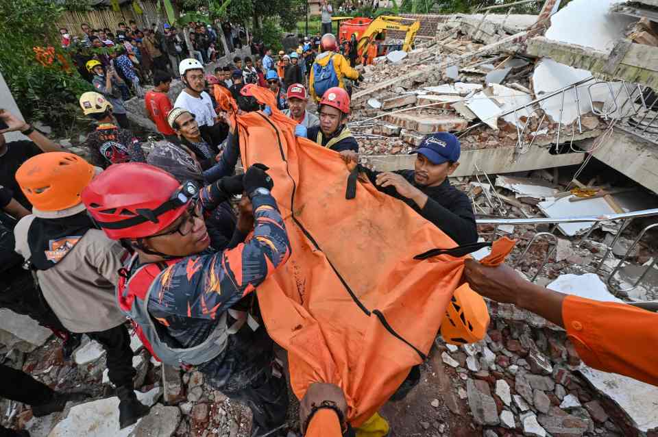 Rescue workers carry the body of a victim in Cianjur