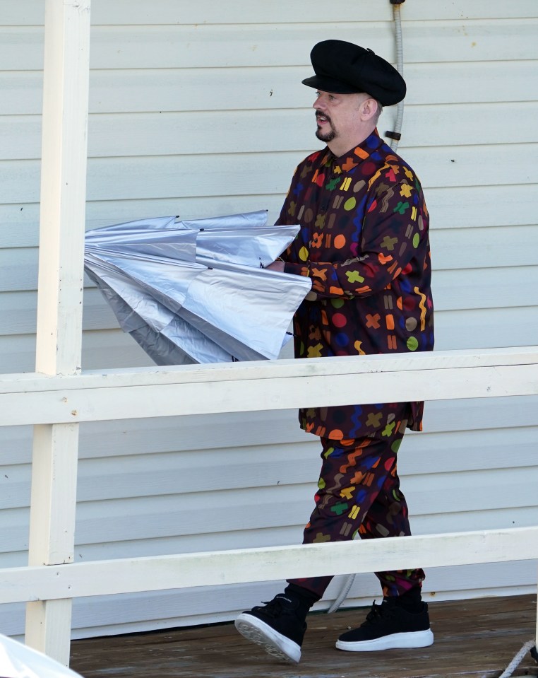 George was snapped in a multi-coloured outfit - brandishing an umbrella