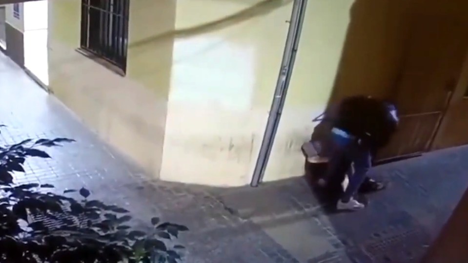 The attacker appears to go through the woman's possessions while she is slumped on the floor