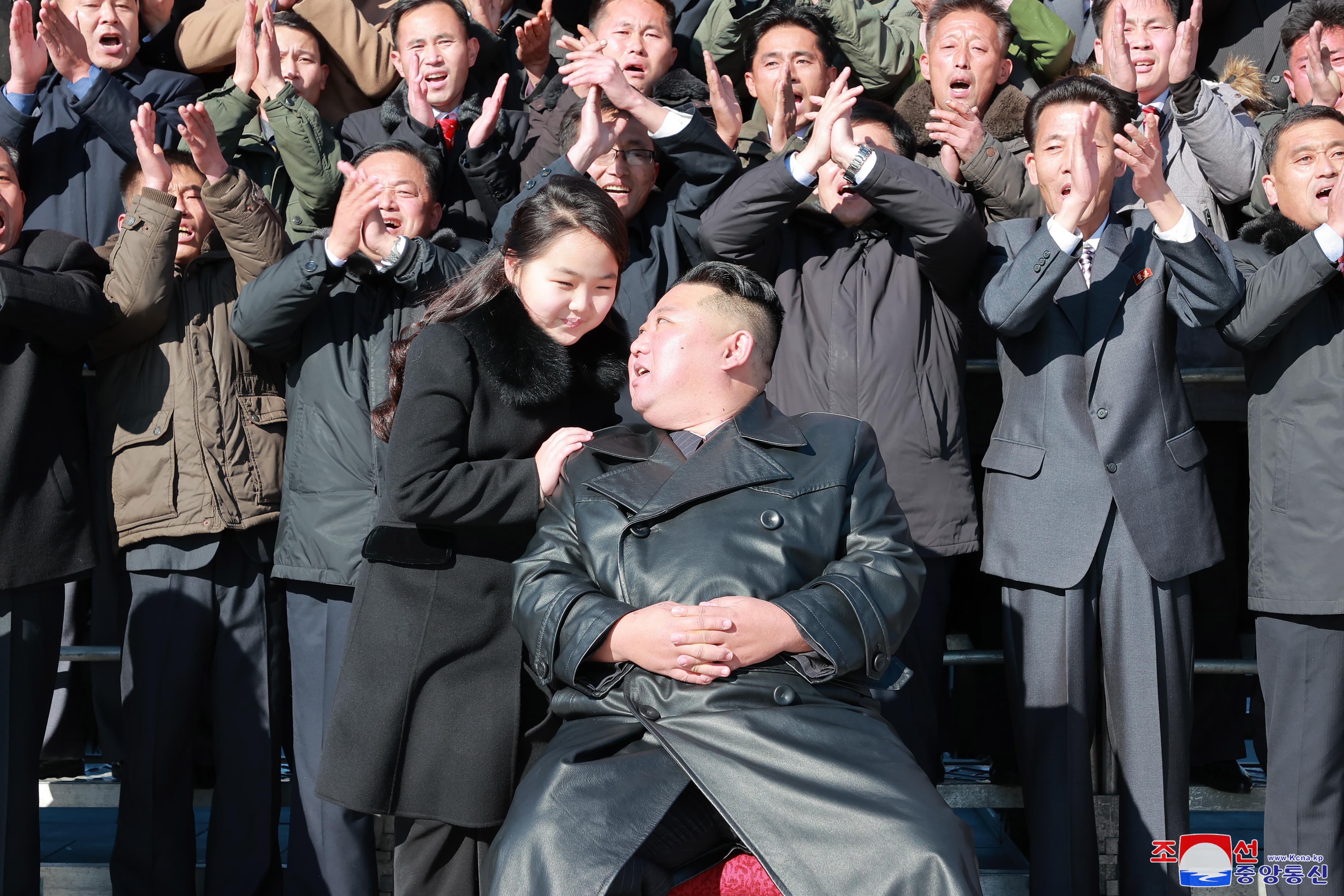 Kim speaks with his daughter as his cronies clap