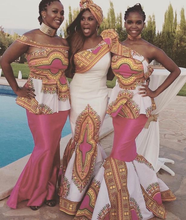 a woman in a white dress stands next to two other women in pink dresses