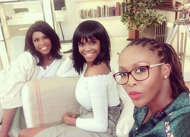 three women are posing for a picture while sitting on a couch