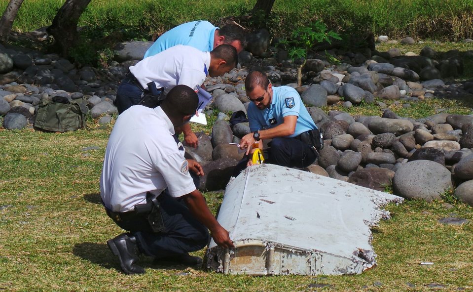 Police inspect a piece of plane debris found on the beach in Saint-Andre, on the French Indian Ocean island of La Reunion