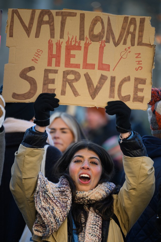 A woman holds a placard as health services gather to demonstrate outside St Thomas’ hospital in Westminster