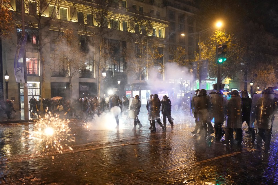 Riot police officers advance on the Champs-Elysees after the World Cup final