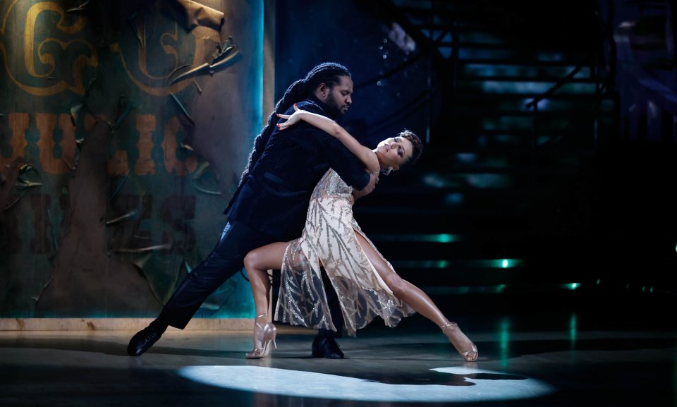 a man and a woman are dancing in front of a sign that says ' g ' on it