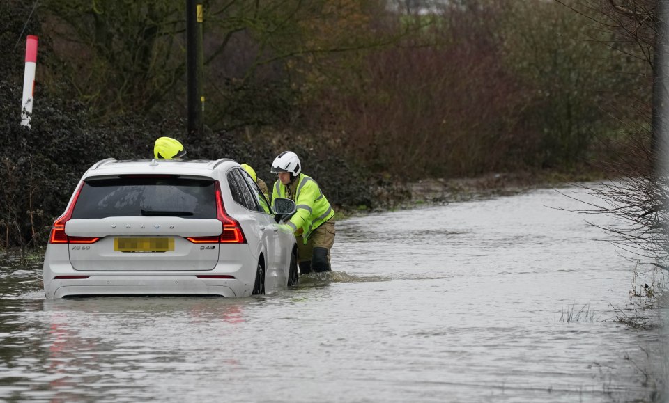 Rescuers help push a stranded motorist out of a flooded road near Billericay