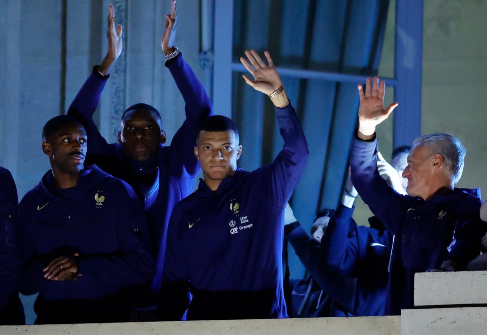 A frustrated-looking Mbappe waves to the crowd from the Hotel Crillon alongside team-mates