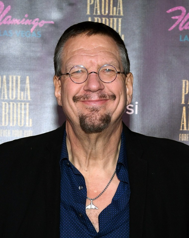 a man wearing glasses stands in front of a paula abdul poster