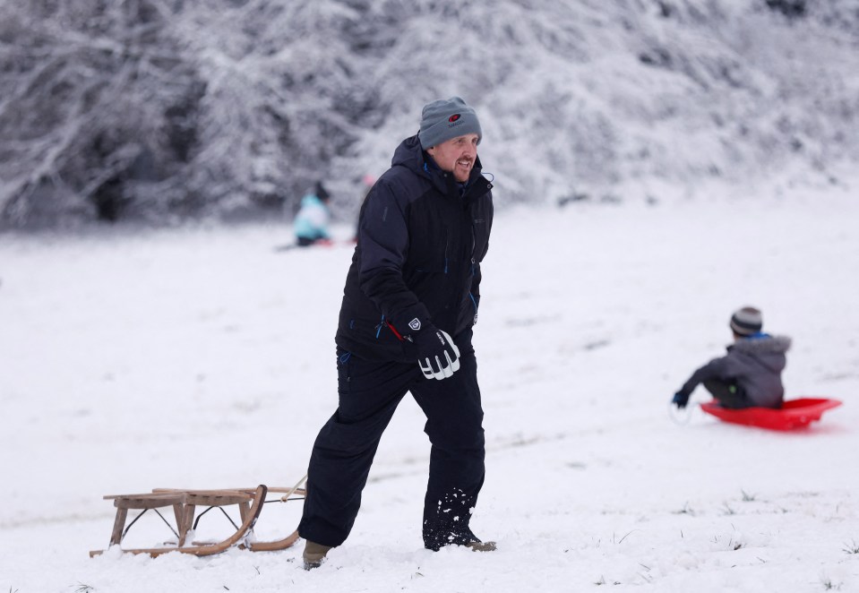 A man tows a toboggan as cold weather continues in Hertford