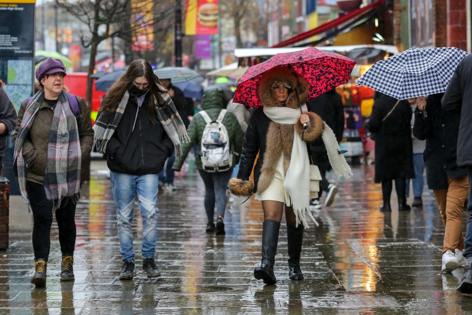 Pedestrians sheltered under umbrellas during rainfall in Camden, north London