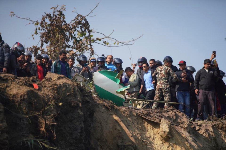 Locals watch the wreckage of the passenger plane being recovered