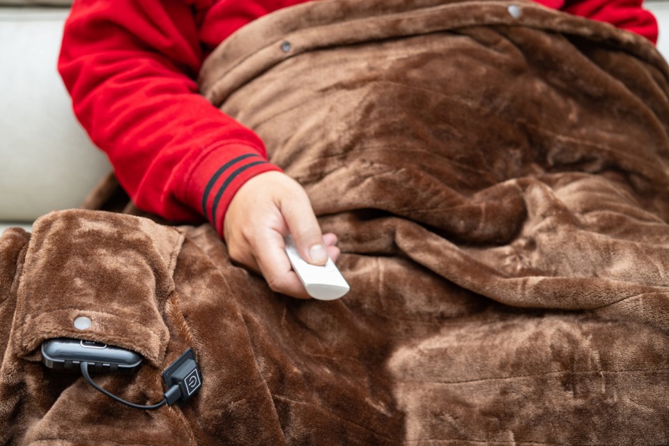 Person using a heated blanket with a remote control.