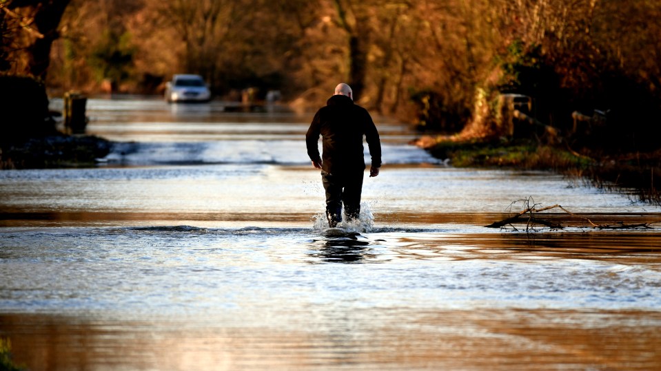 A man wades through floodwater at Apperley near the River Severn and Tewkesbury, Gloucestershire