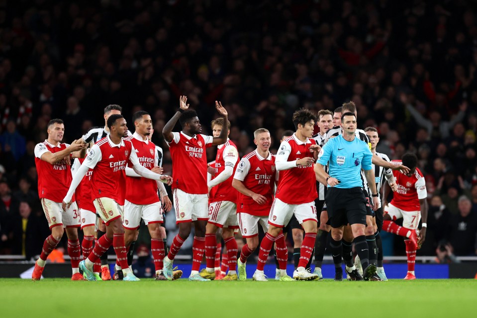 Arsenal players surround the referee Andy Madley after a late penalty appeal was rejected